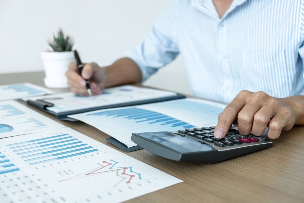 A Man Is Using a Calculator While Writing on A Clipboard — Early Bird Accounts in Tamworth, NSW