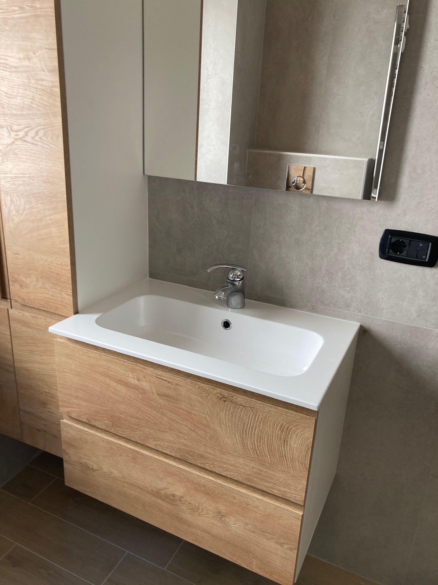 Un bagno con lavandino, specchio e mobiletto.