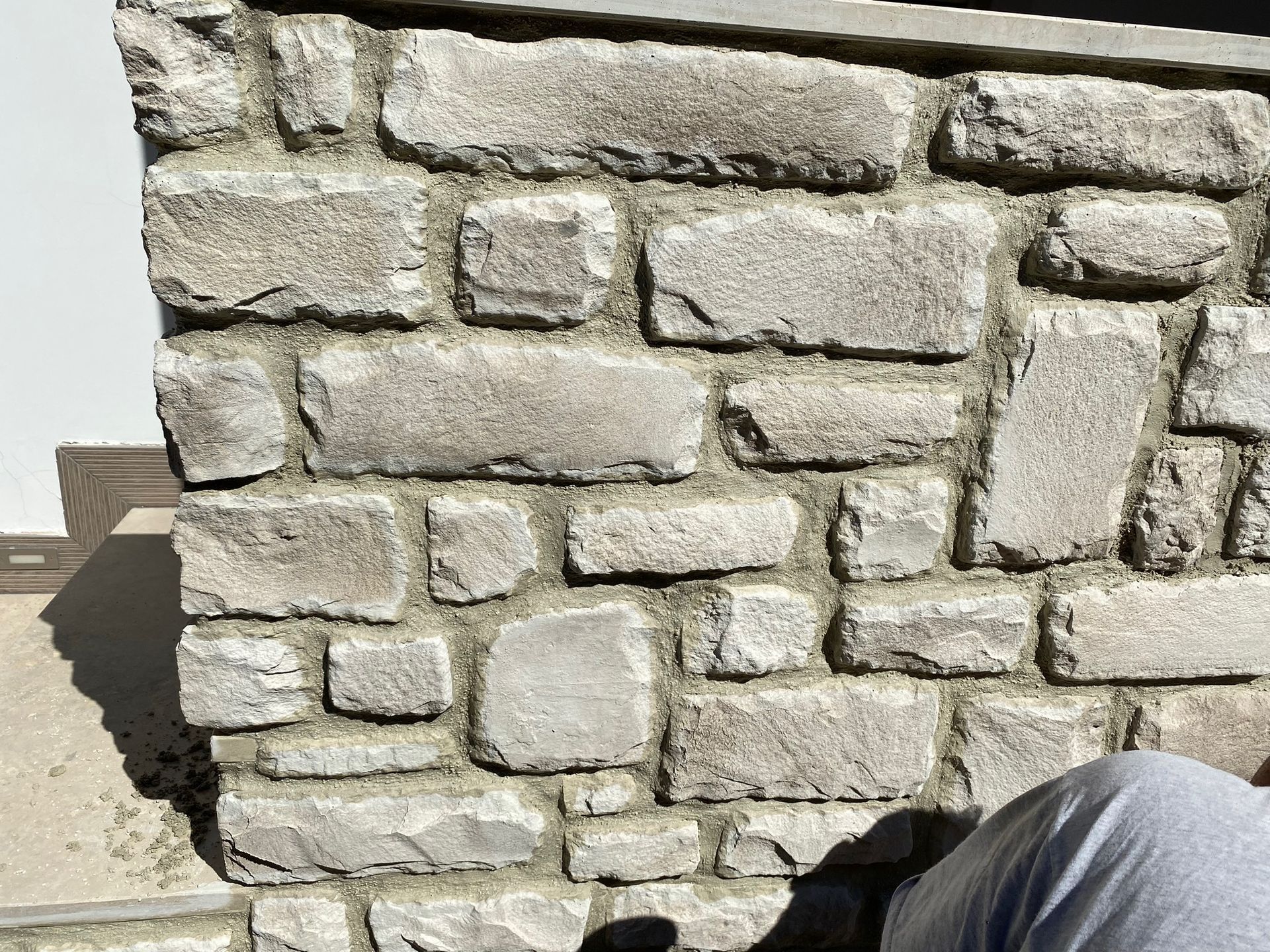 Un uomo sta lavorando su un muro di pietra.