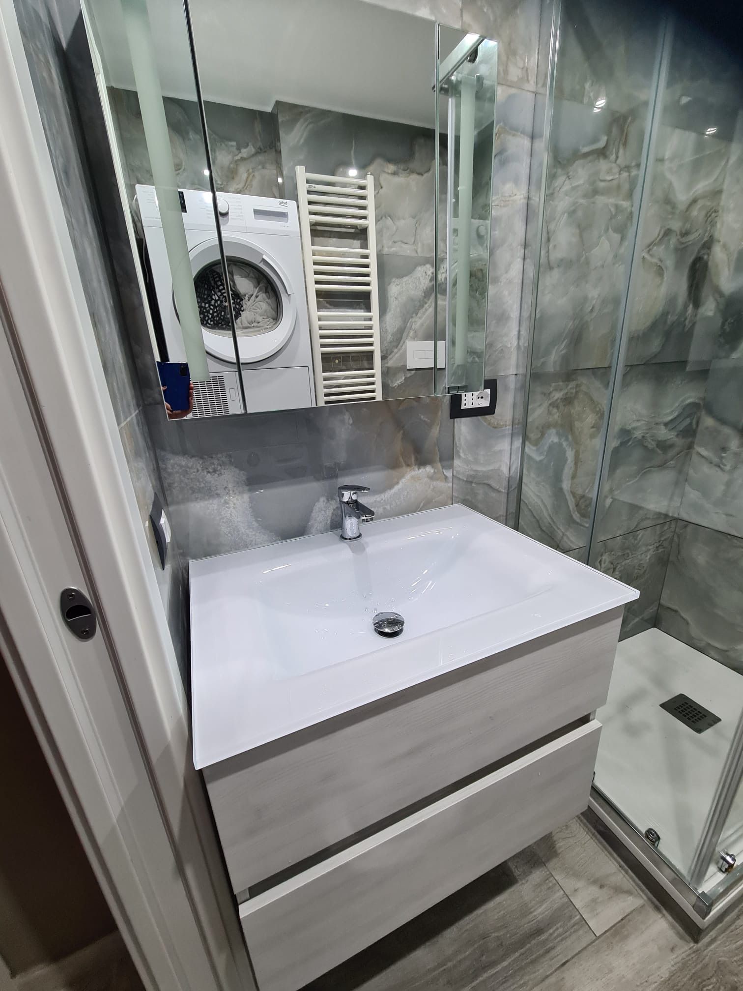 Un bagno con lavandino, specchio, lavatrice e asciugatrice.