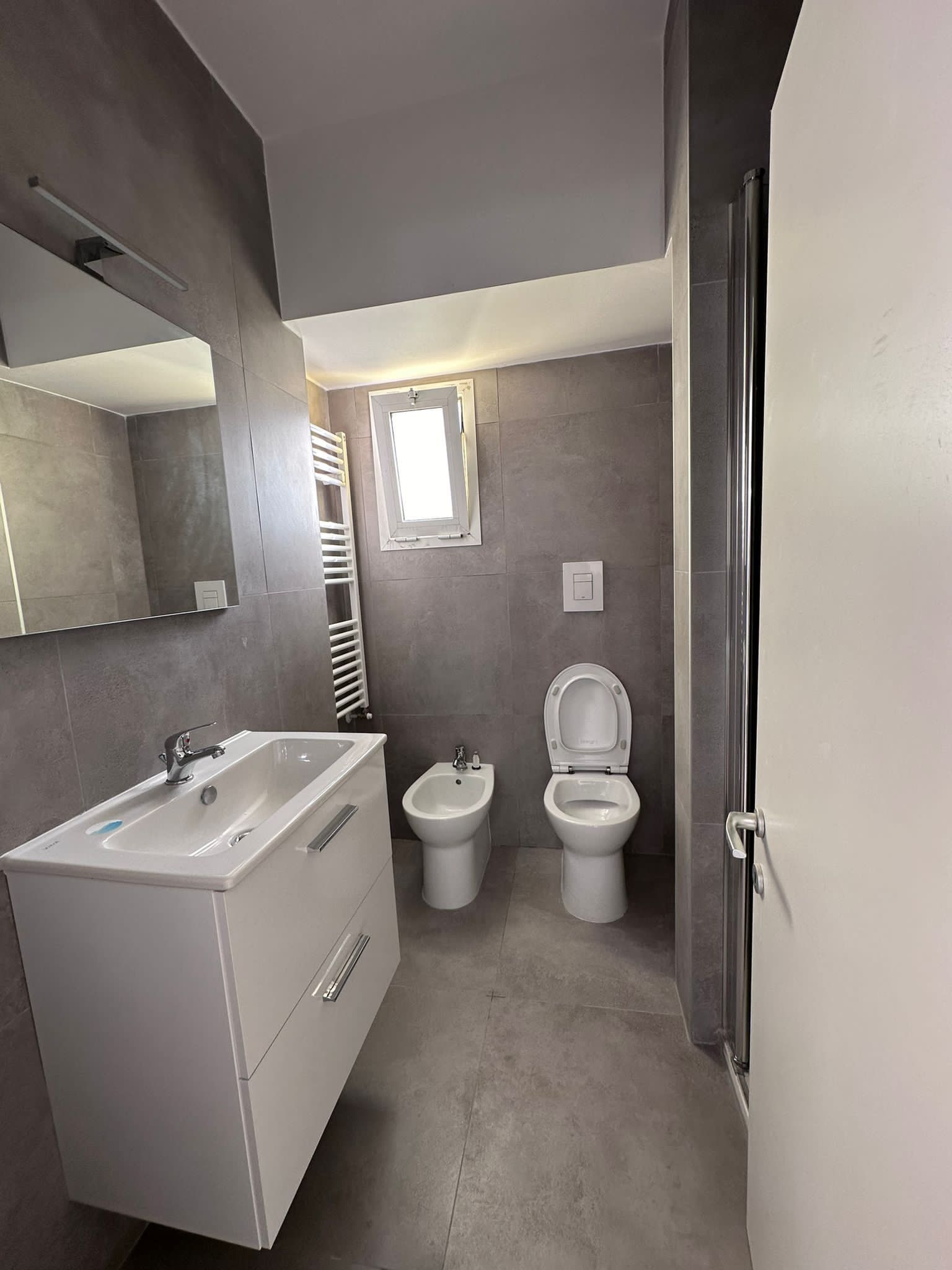 Un bagno con lavandino, water, bidet e specchio