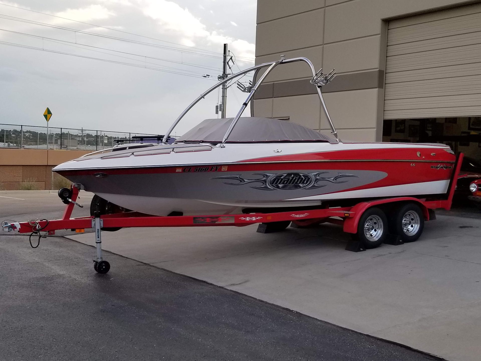 A red and white boat is parked on a trailer