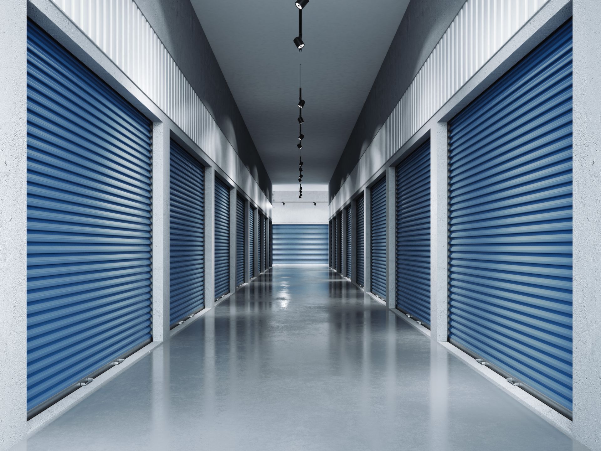 Clean hallway of secure indoor storage units with modern blue rolling doors.