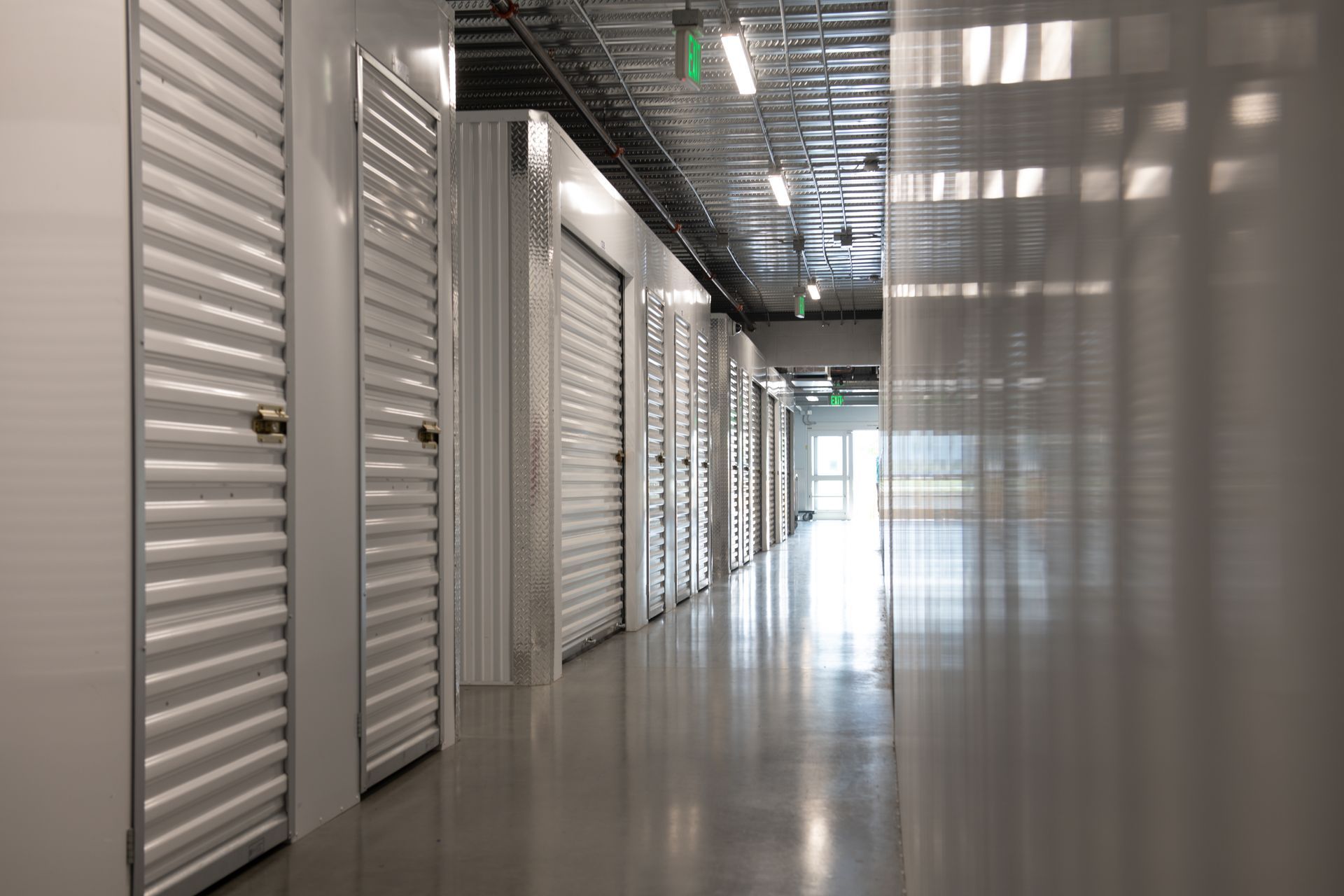 Secure self storage facility hallway featuring polished concrete floors and locked units.