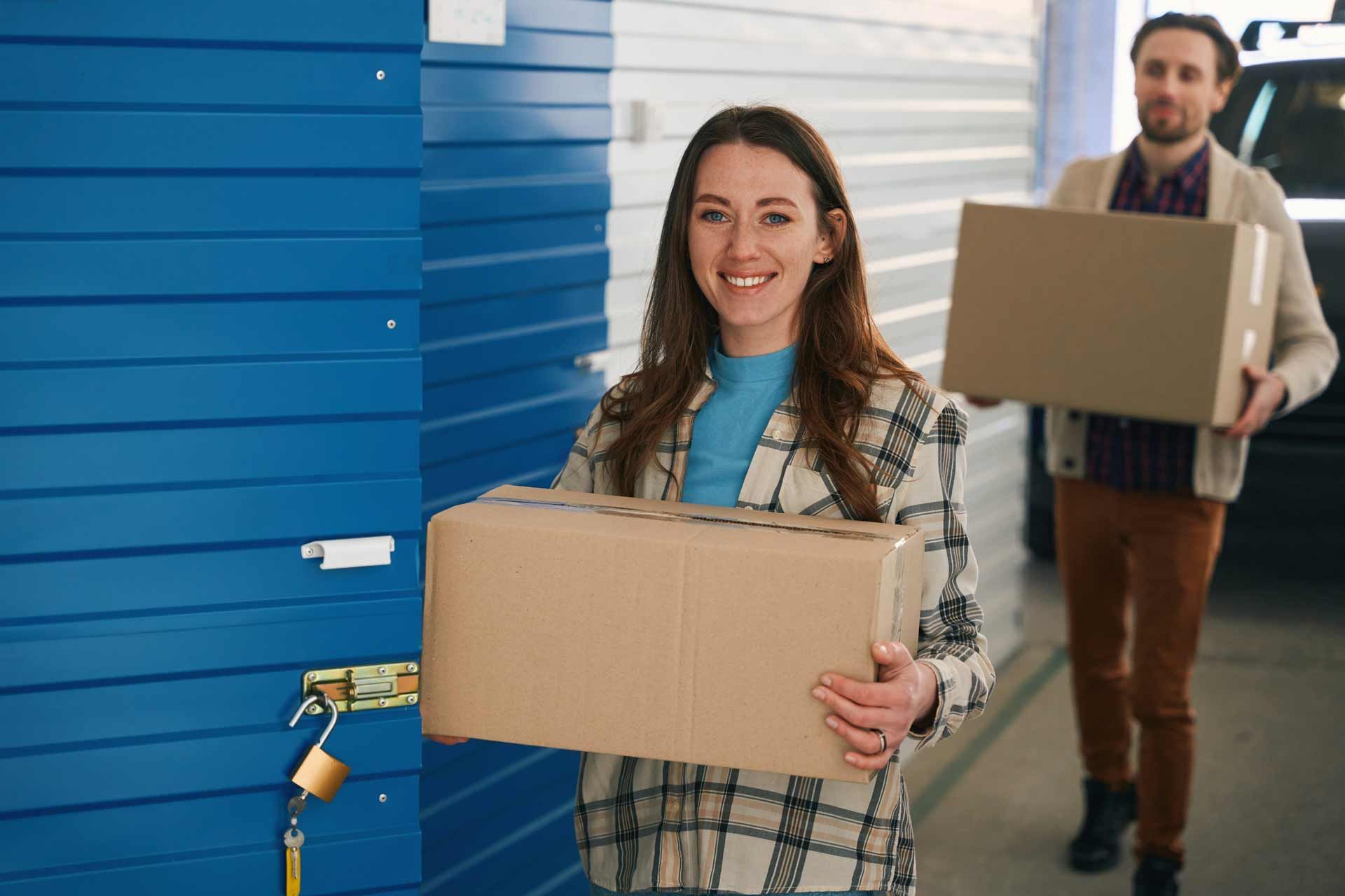 Happy couple carrying cardboard boxes in a self-storage unit in Akron, OH 