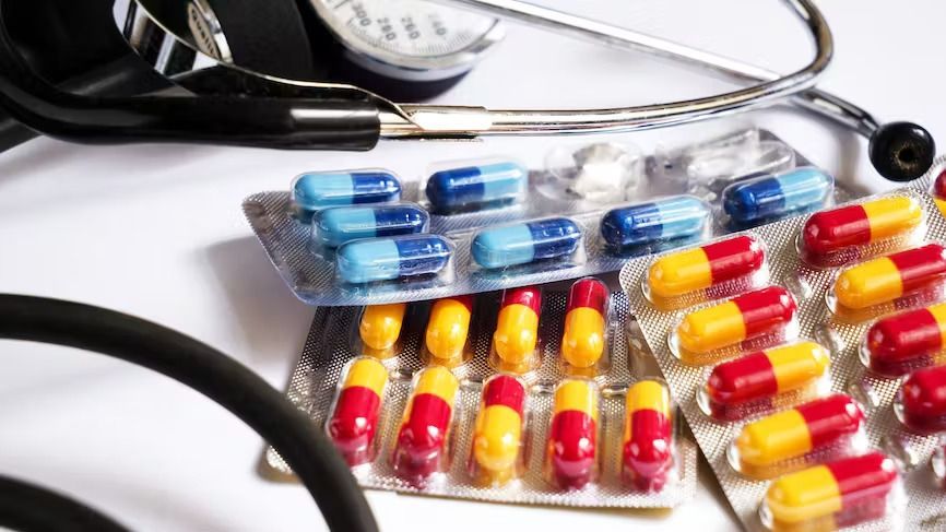Pilules sous blister : bleues, rouges et jaunes, avec un stéthoscope et un manomètre médical.