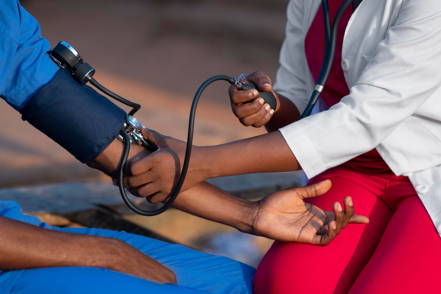 Un professionnel de santé prend la tension artérielle d'un patient à l'aide d'un brassard et d'un stéthoscope.