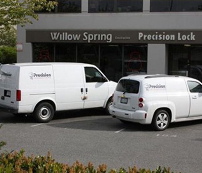 Two Precision Lock service vehicles parked outside Willow Spring Precision Lock storefront