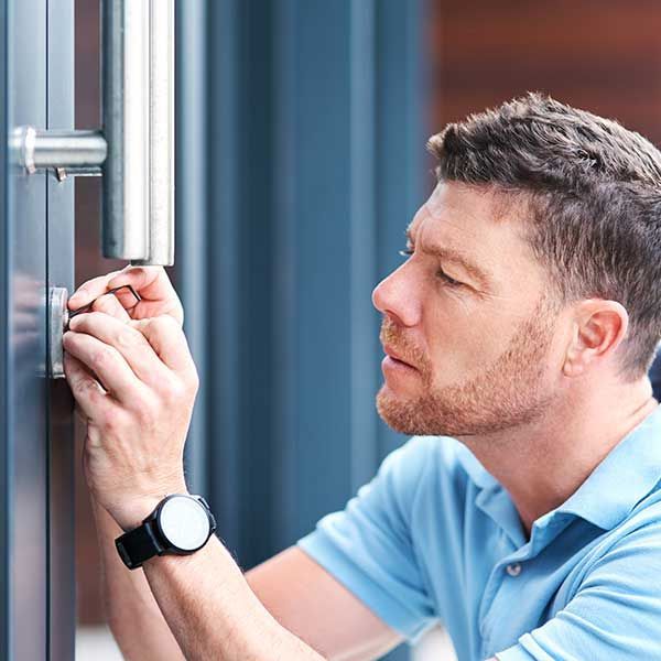 Man in blue polo adjusting lock on a glass door
