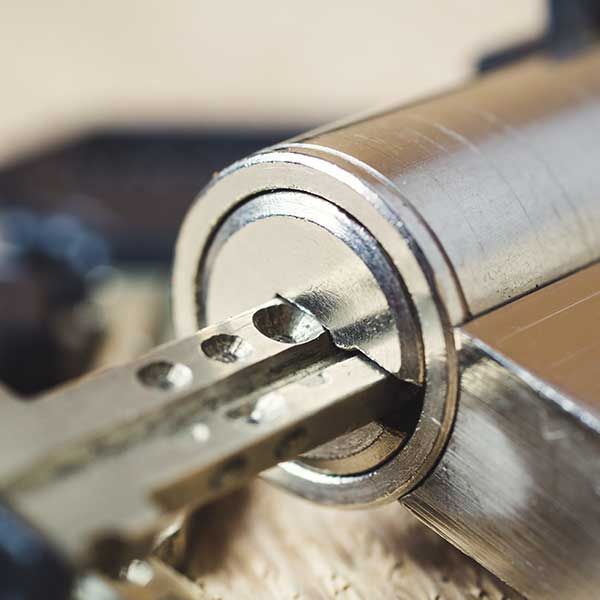 Close-up of a metal key inserted into a silver padlock