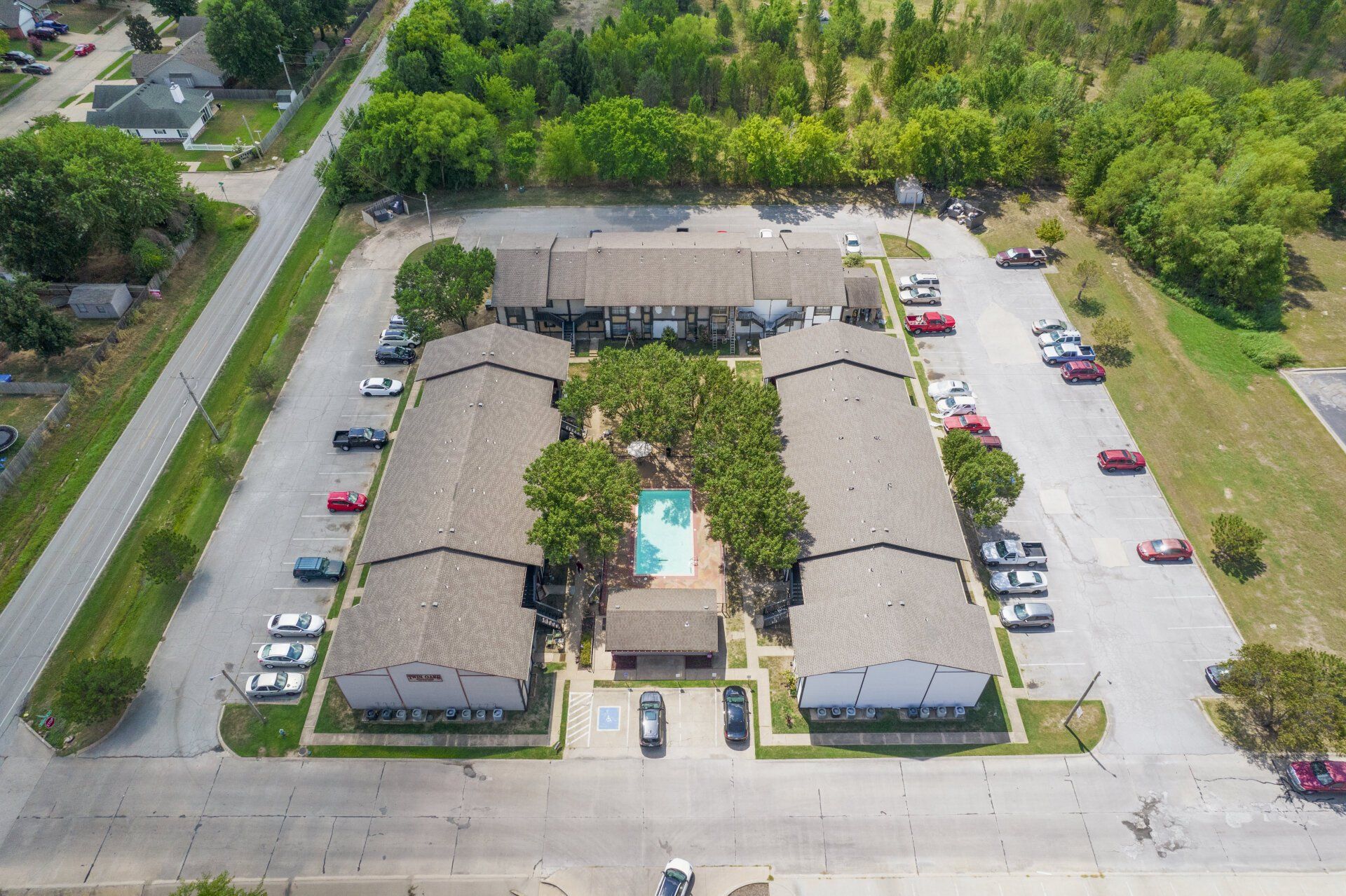 An aerial view of a large apartment complex with a pool in the middle.