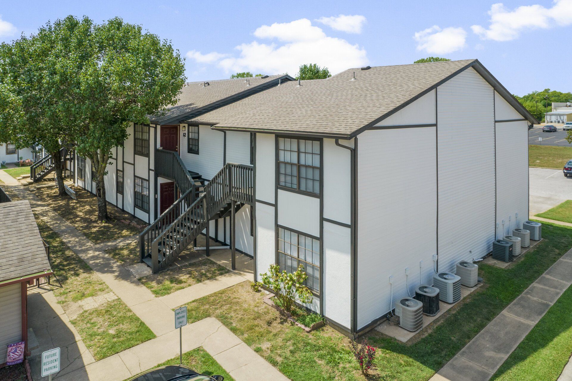 An aerial view of a white apartment building with stairs leading up to the second floor.