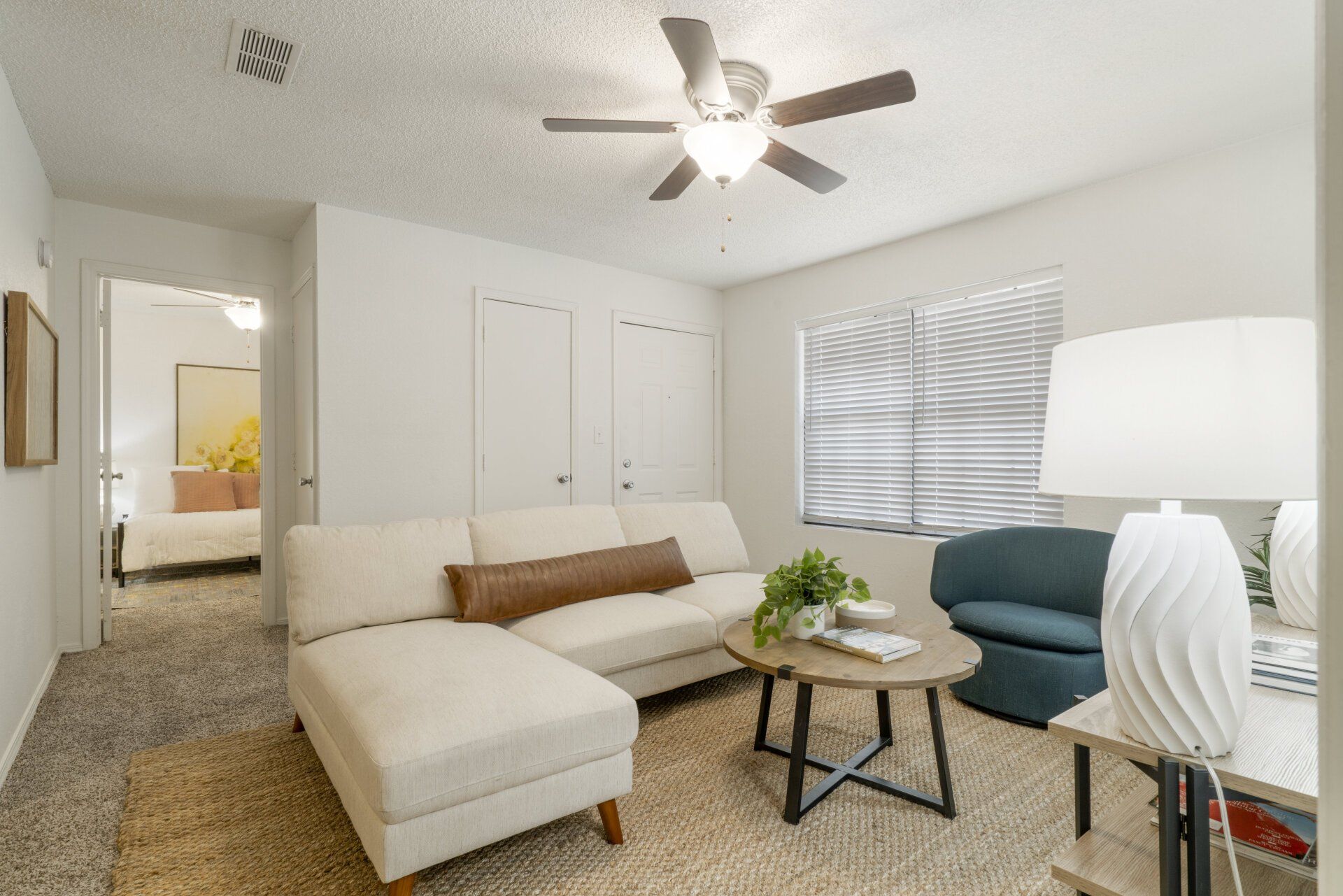 A living room with a couch , chair , coffee table and ceiling fan.