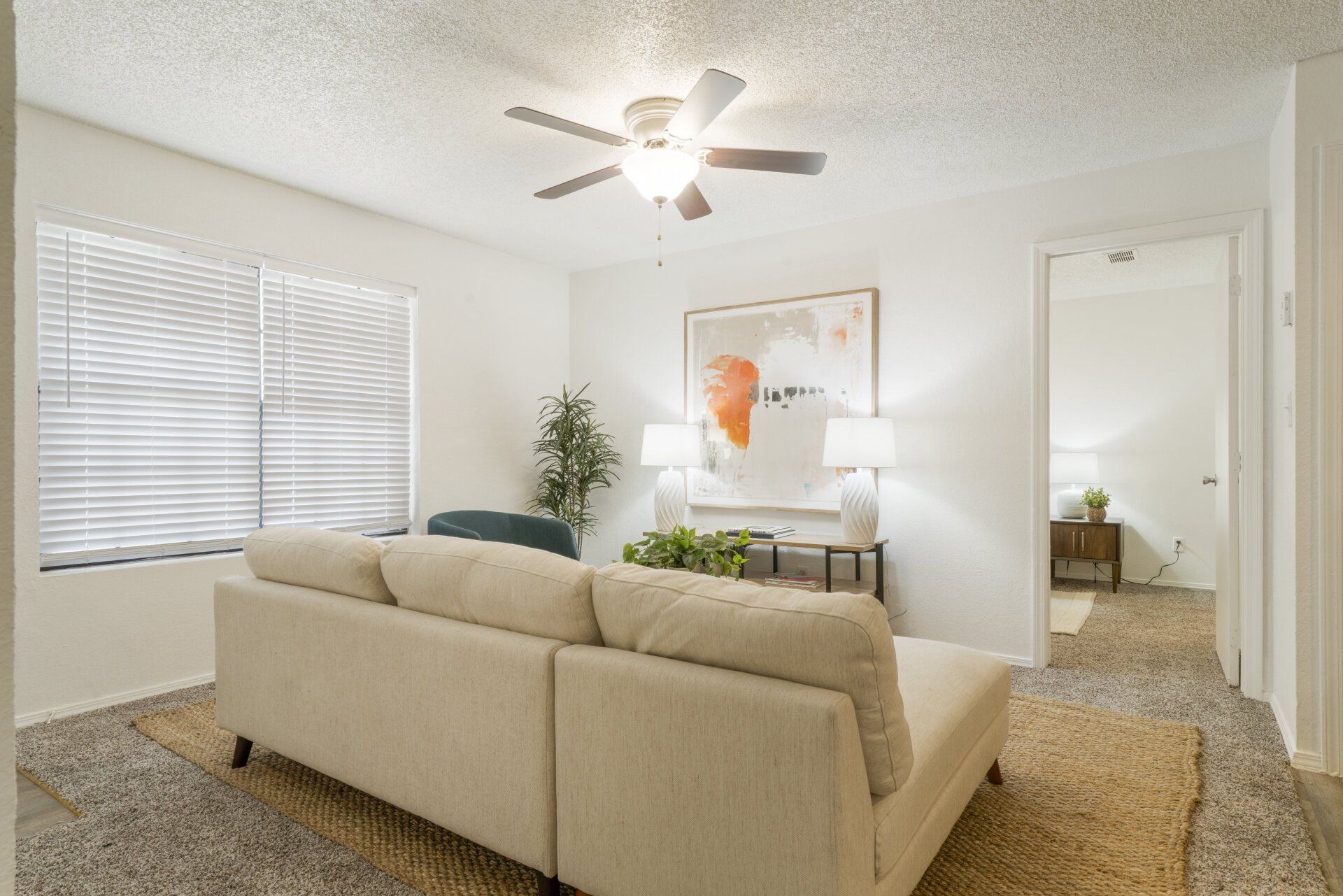 A living room with a couch and a ceiling fan.