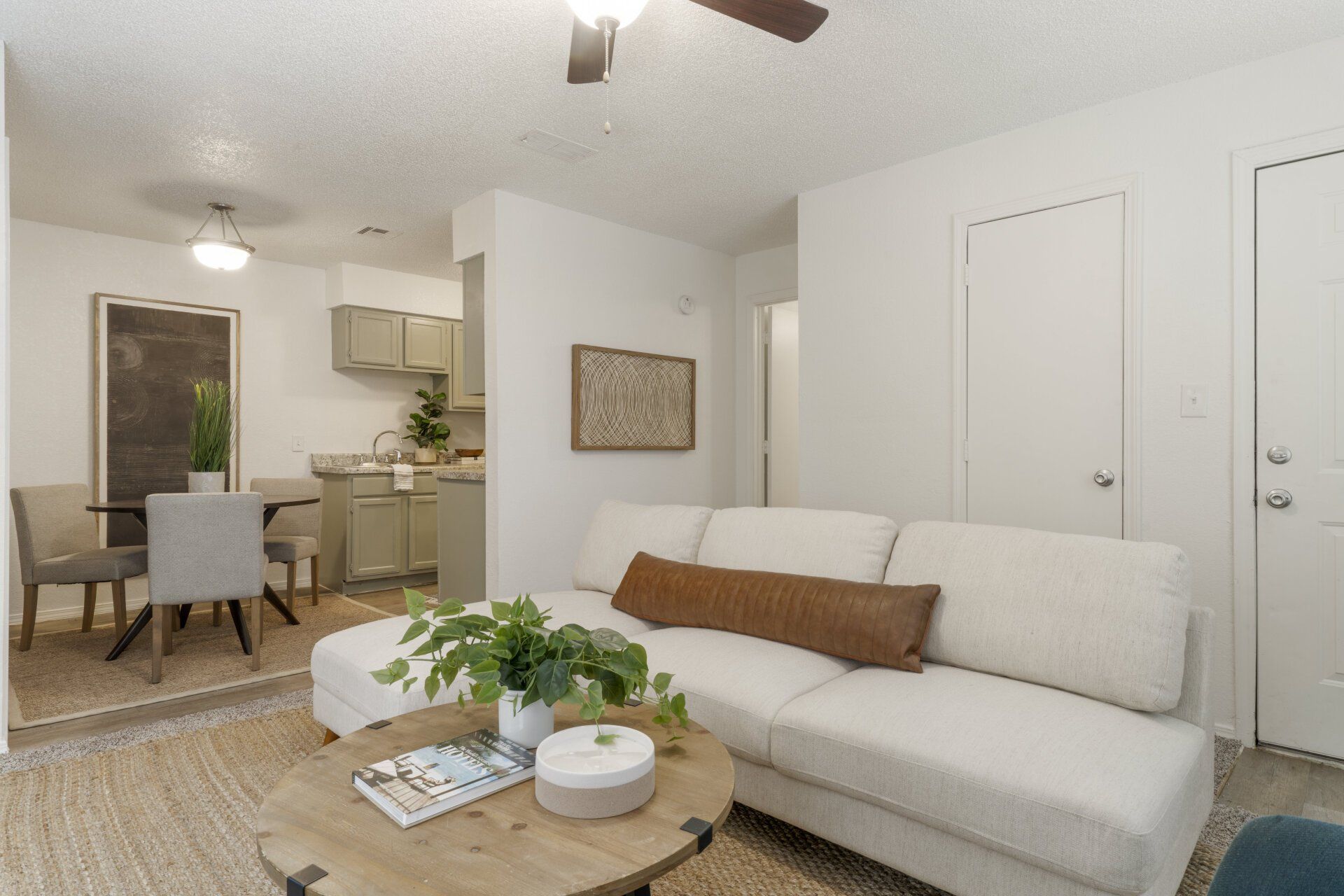 A living room with a couch , coffee table , chairs and a ceiling fan.
