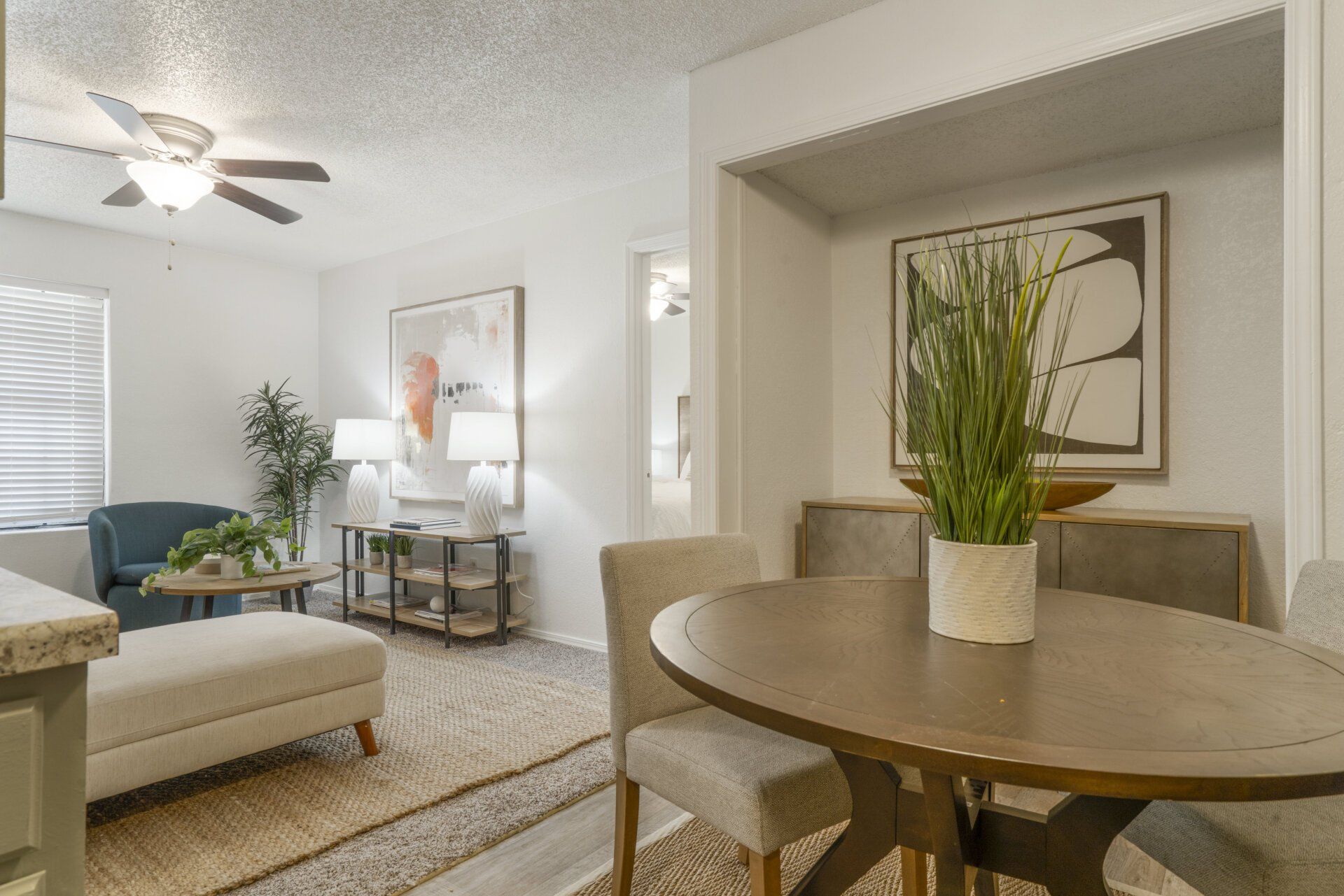 A living room with a round table and chairs and a ceiling fan.