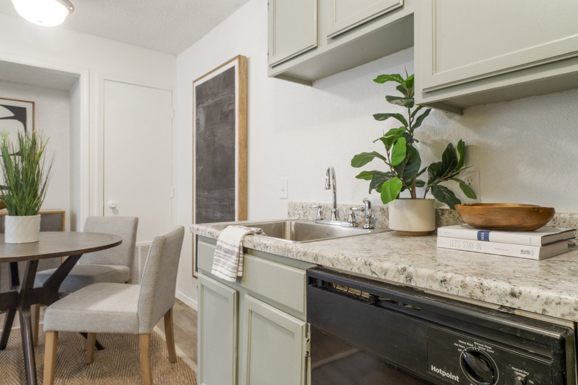 A kitchen with a sink , dishwasher , table and chairs.