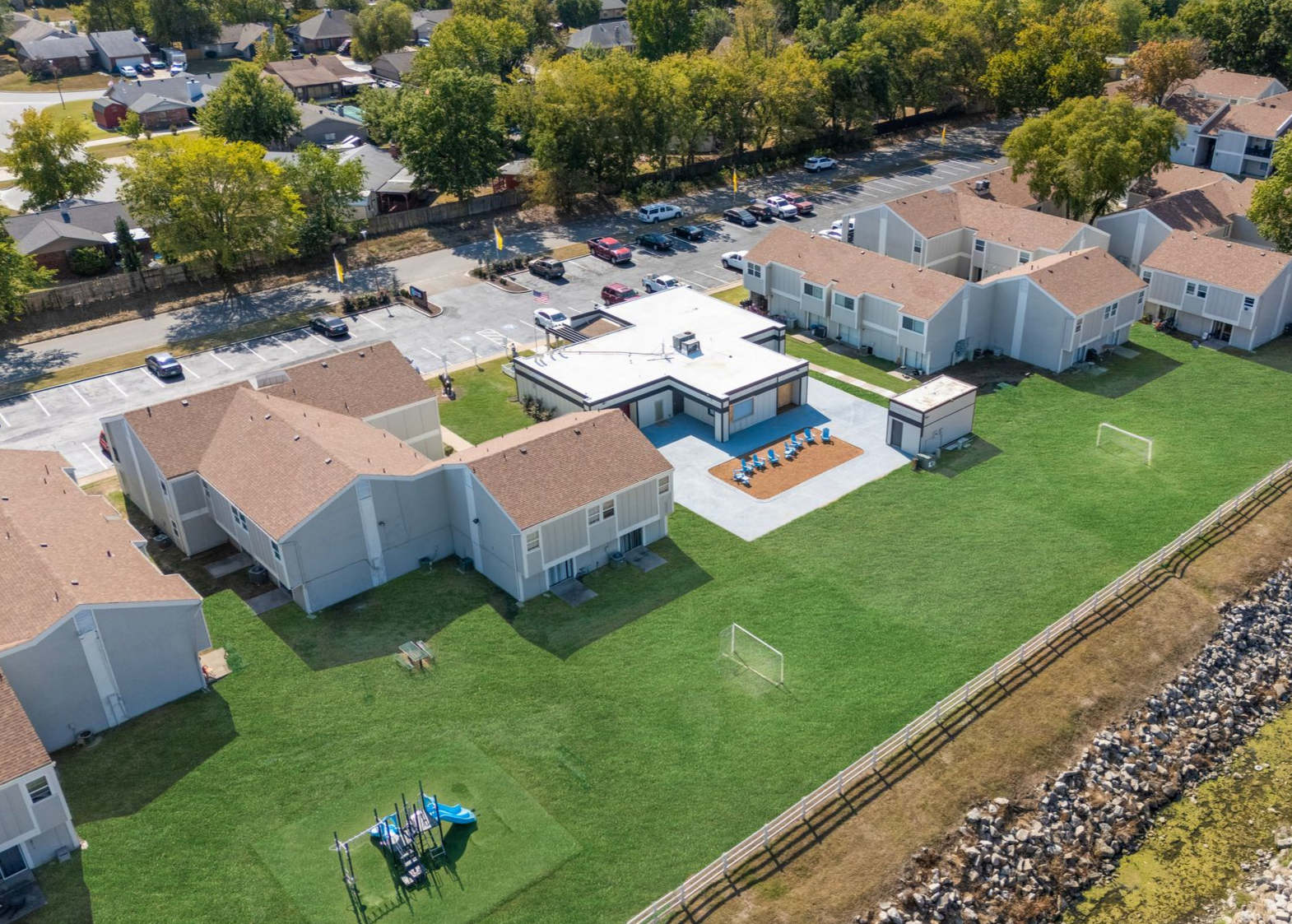 a row of apartment buildings with a lush green lawn in front of them .