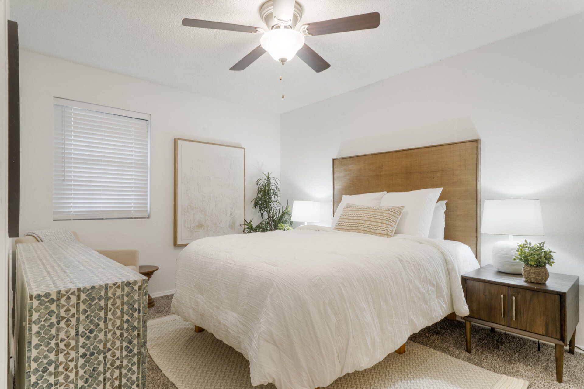 A bedroom with a bed , nightstand , dresser and ceiling fan.