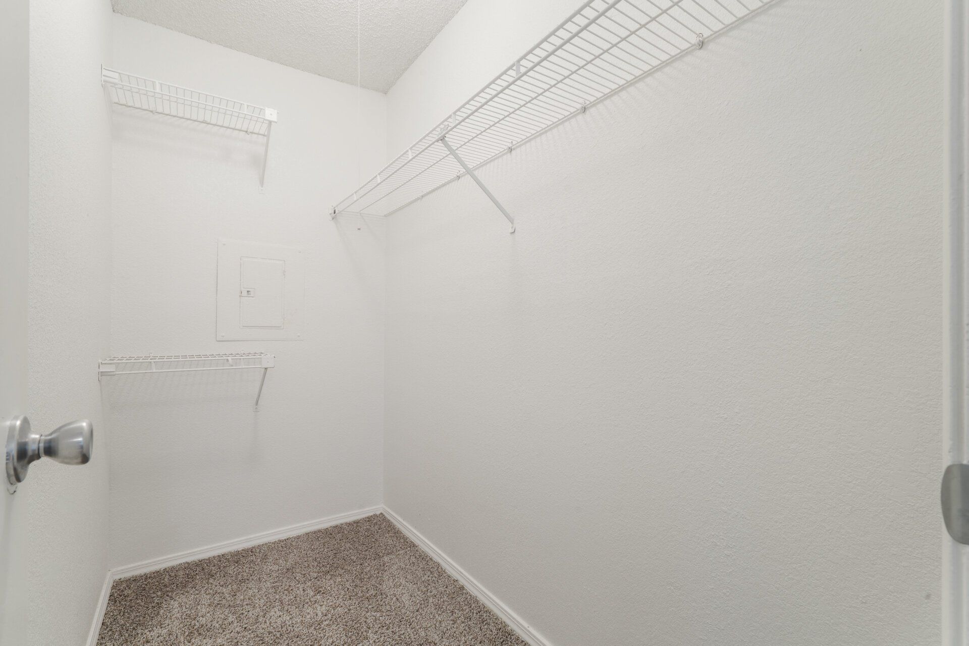 An empty walk in closet with a laundry basket and a door.