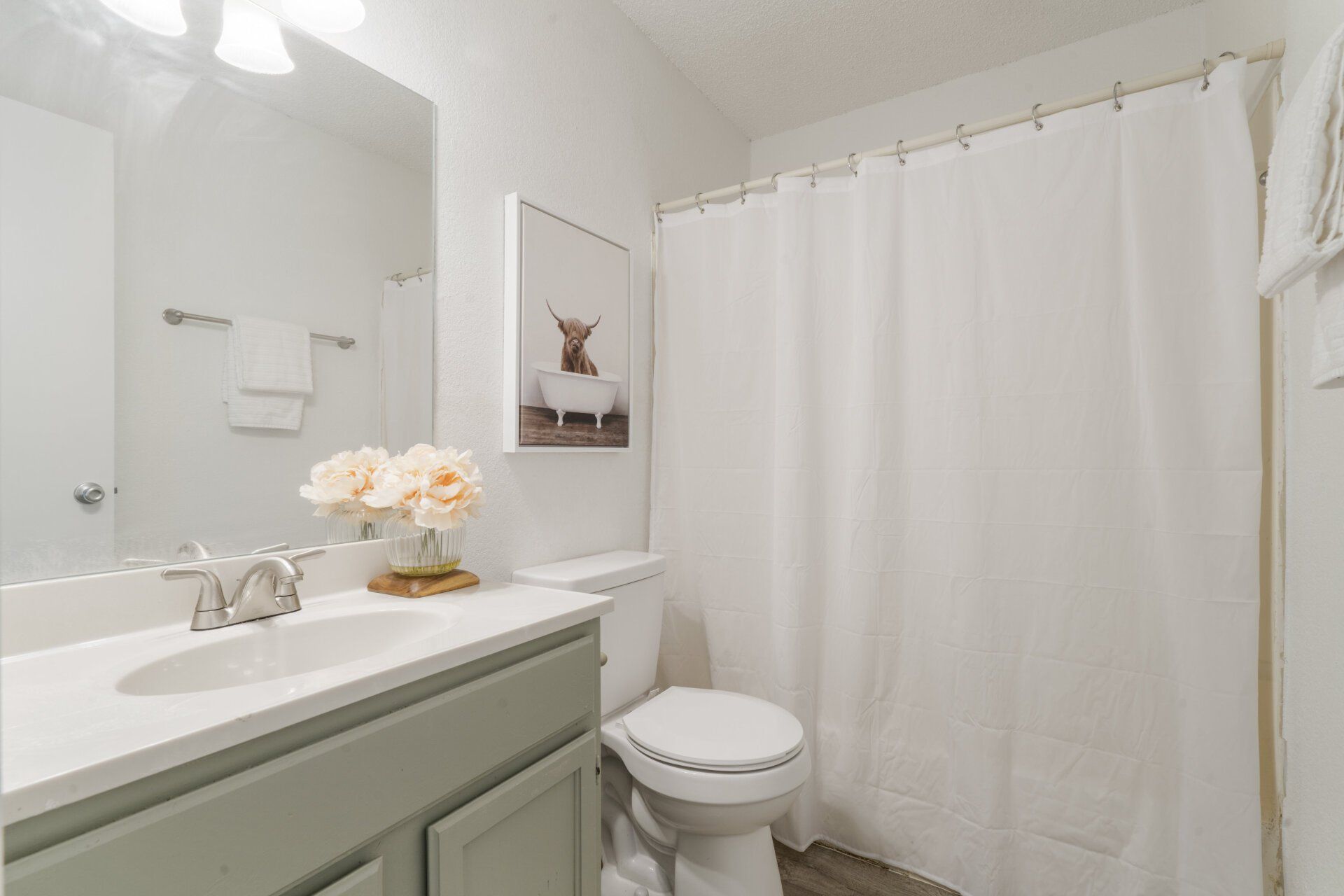 A bathroom with a sink , toilet , shower curtain and mirror.