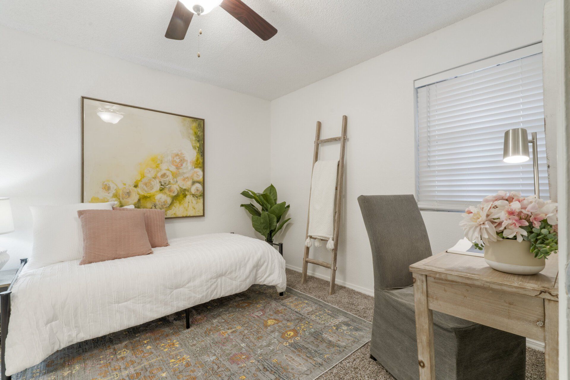 A bedroom with a bed , desk , chair and a painting on the wall.