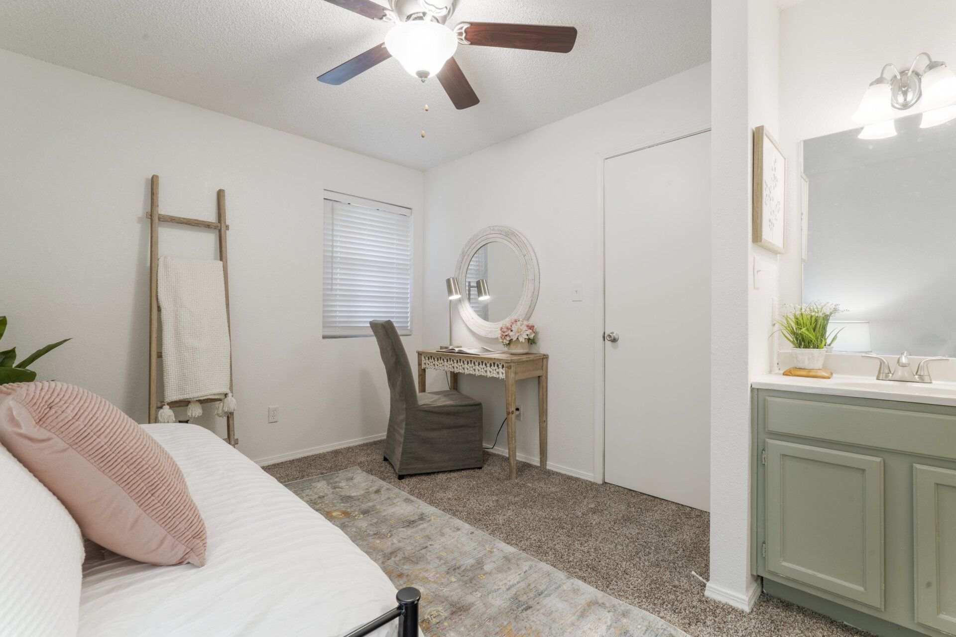 A bedroom with a bed , desk , chair and ceiling fan.