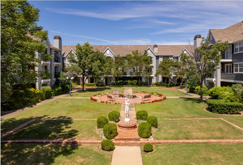 An aerial view of a large apartment complex with a fountain in the middle of the courtyard.