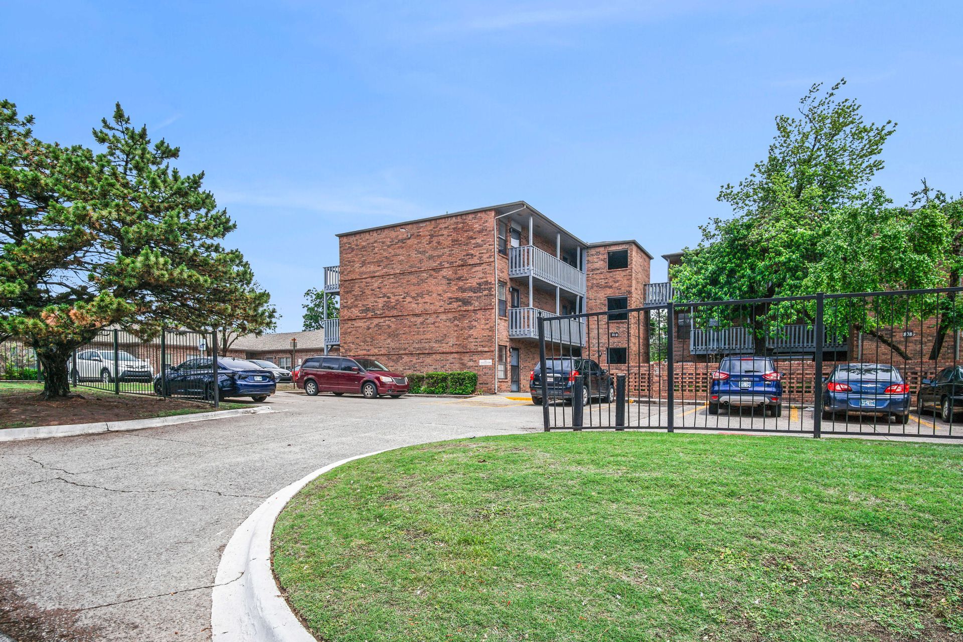 A brick apartment building with cars parked in front of it