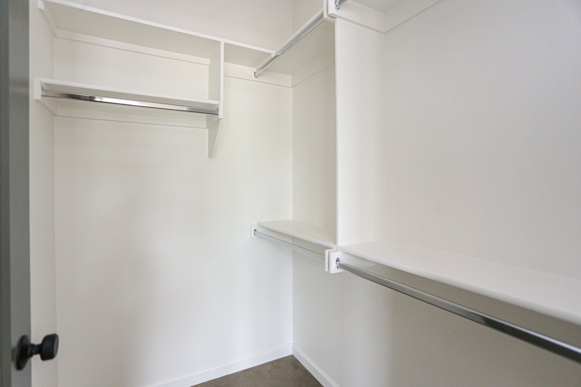An empty walk in closet with shelves and clothes racks.