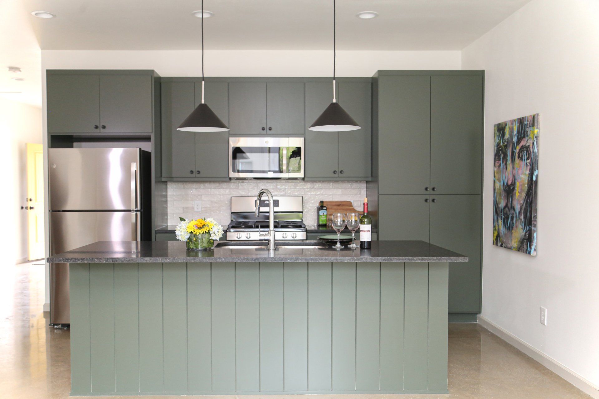 A kitchen with green cabinets and a stainless steel refrigerator
