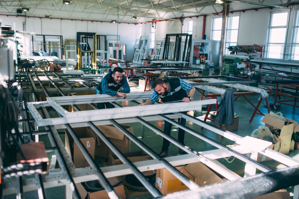 Two Men Are Working On A Piece Of Metal In A Factory — New England Glass & Aluminium In Guyra, NSW