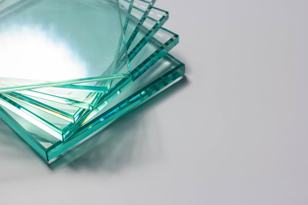 Several Pieces Of Glass Are Stacked On Top Of Each Other On A Table — New England Glass & Aluminium In Coffs Harbour, NSW