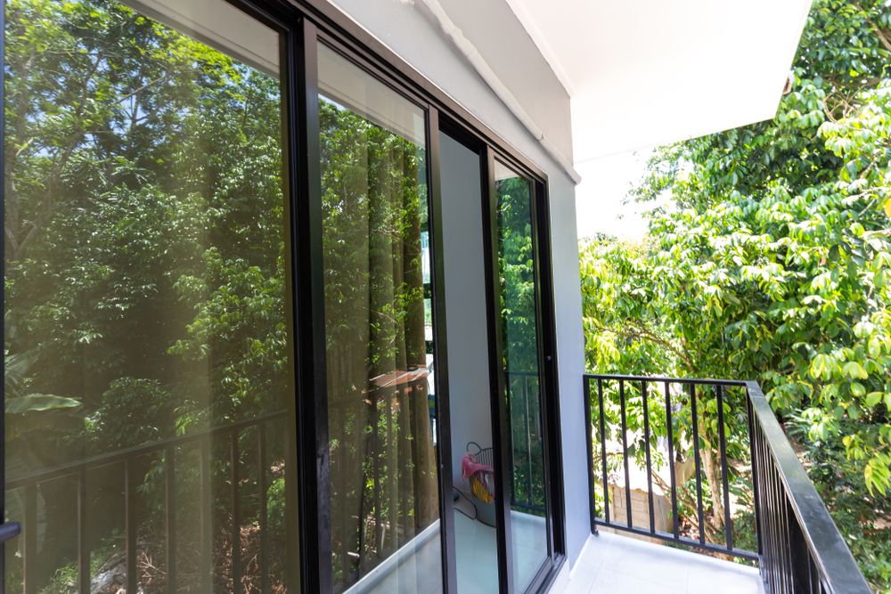 A Balcony With Sliding Glass Doors And Trees In The Background — New England Glass & Aluminium In Tamworth, NSW
