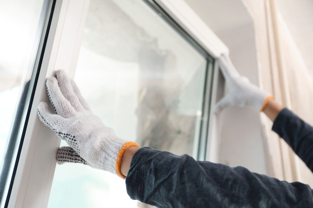 A Person Wearing Gloves Is Cleaning A Window — New England Glass & Aluminium In Glen Innes, NSW