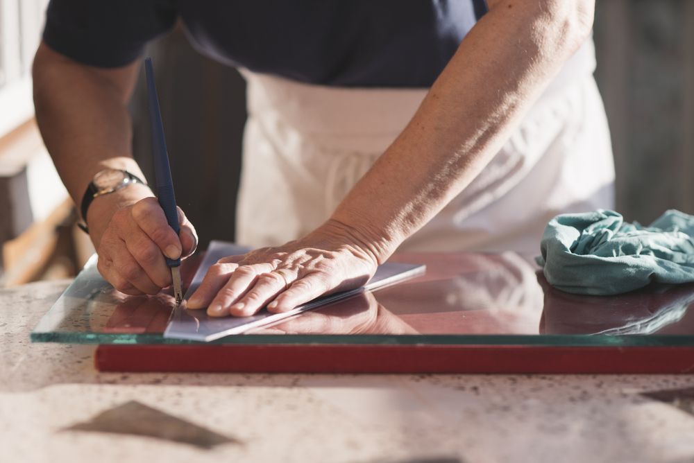 A Person Is Cutting A Piece Of Glass With A Pencil — New England Glass & Aluminium In Glen Innes, NSW