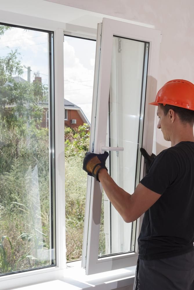 A Man Wearing a Hard Hat Is Installing a Window — New England Glass & Aluminium In Walcha, NSW