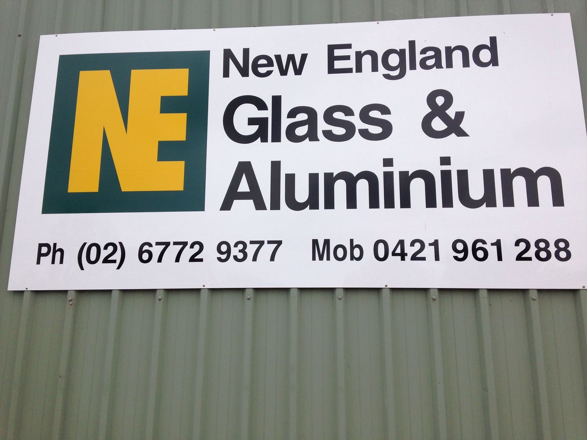 A Man And A Woman Are Standing In Front Of A New England Glass And Aluminum Office — New England Glass & Aluminium In Armidale, NSW