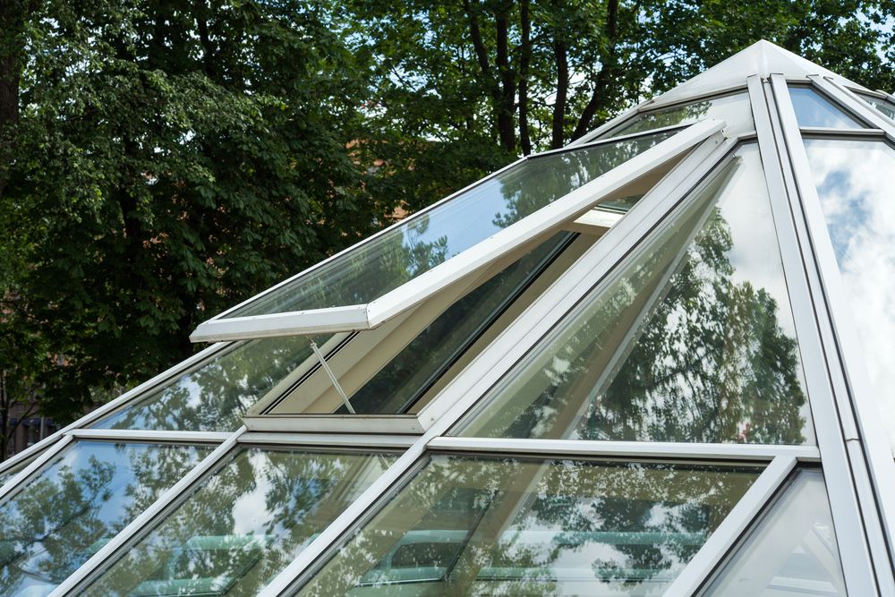 A Greenhouse With A Glass Roof And Trees In The Background — New England Glass & Aluminium In Glen Innes, NSW