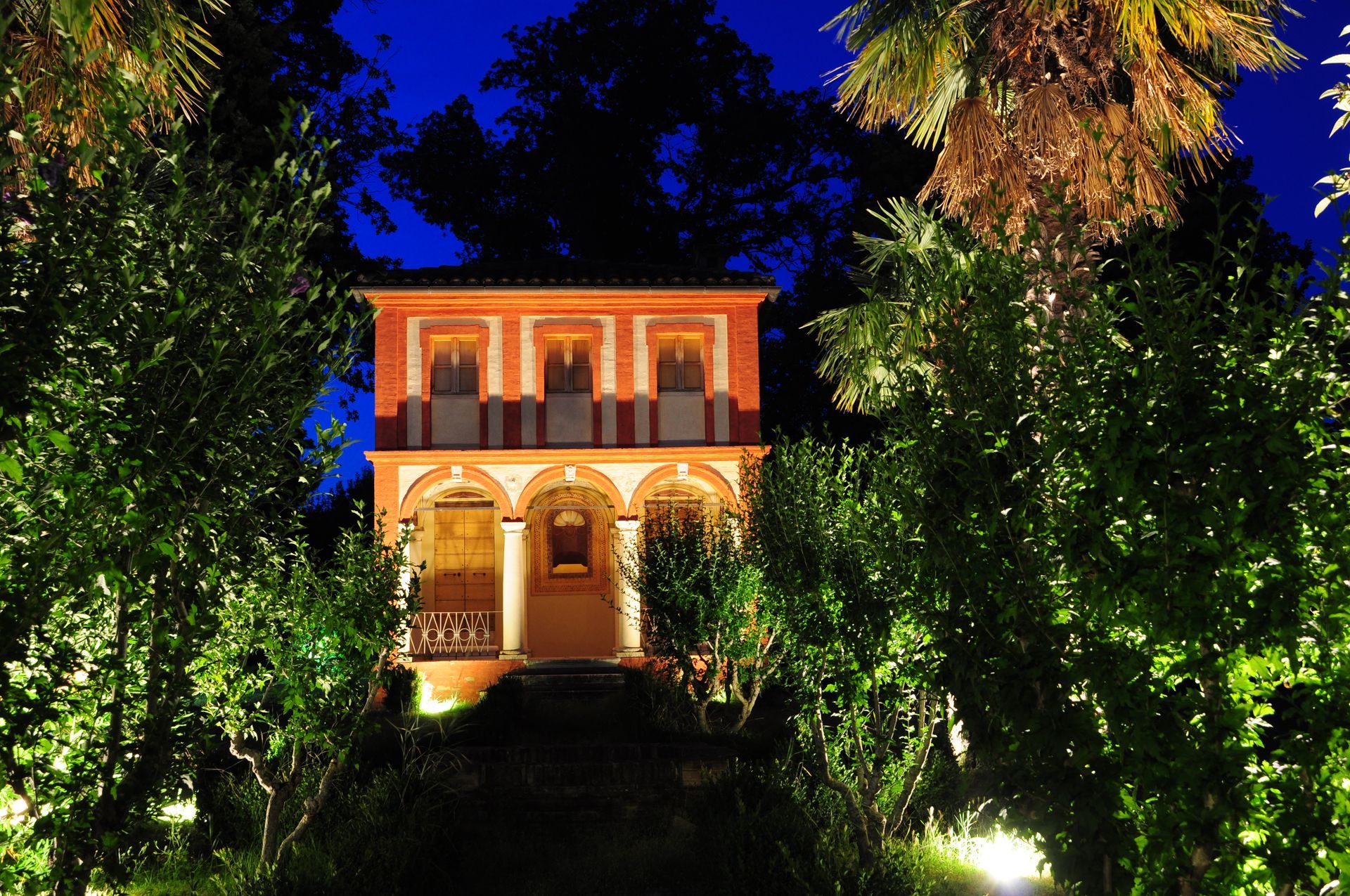 una casa è illuminata di notte e circondata da alberi