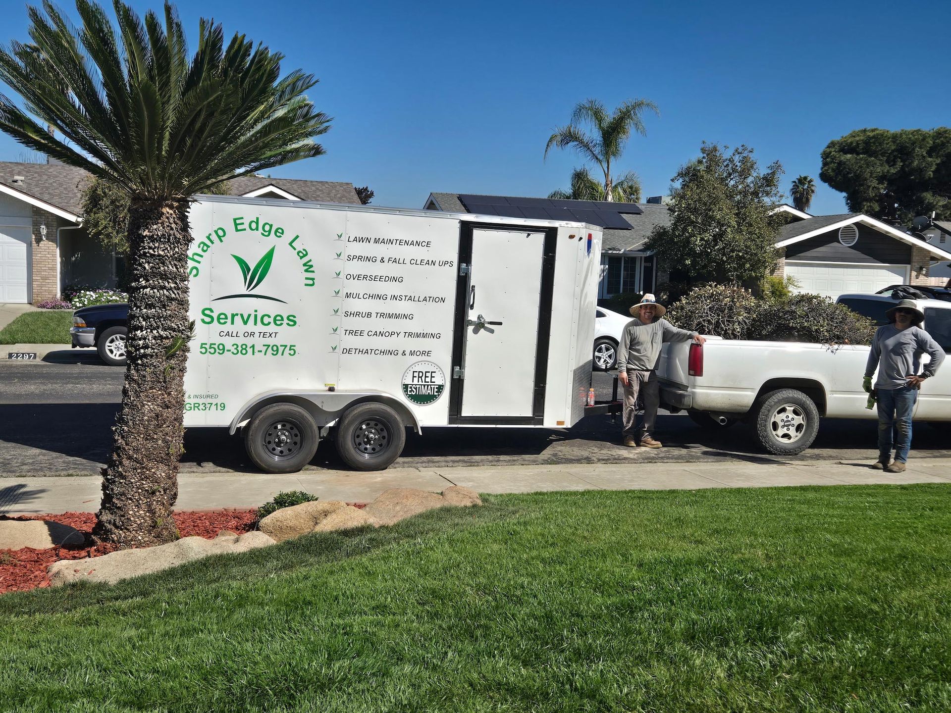 Two workers stand beside a white truck and trailer labeled 