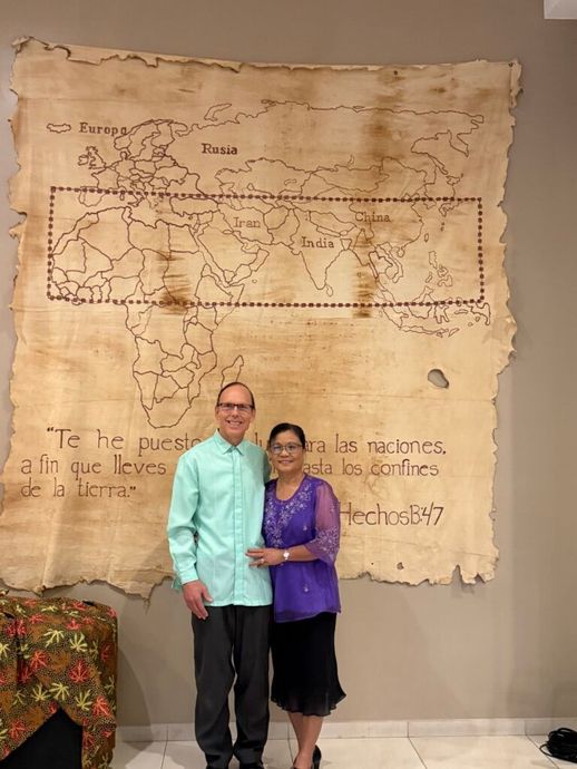 Two people standing together in front of a large world map display on a wall