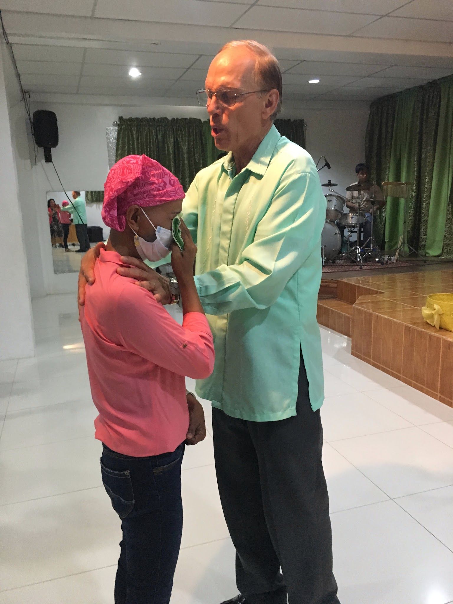 Two smiling children holding hands and facing each other indoors, wearing light yellow and pink shirts