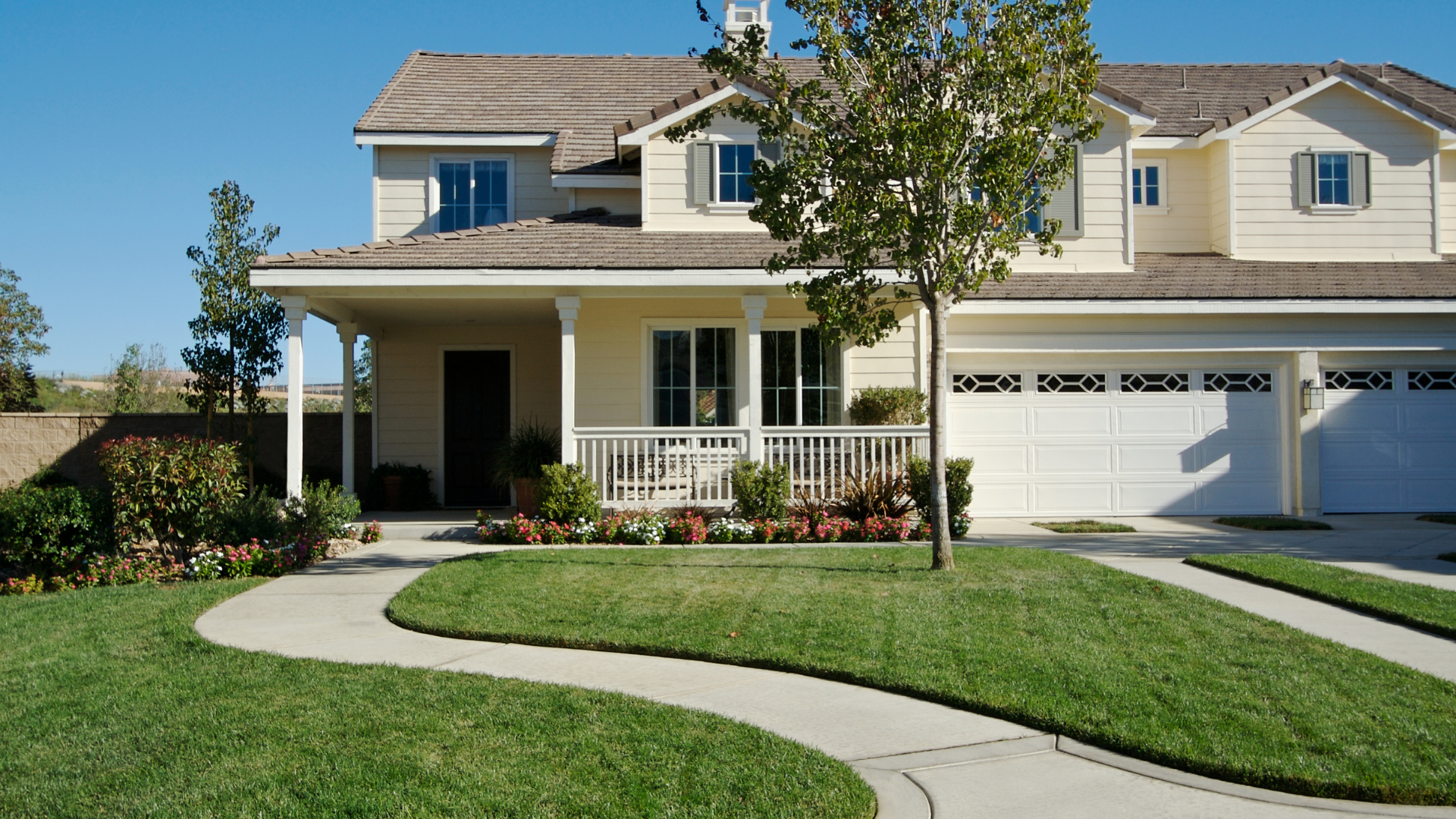 A two-story house with a lawn, a winding sidewalk, and a driveway, sunny day.