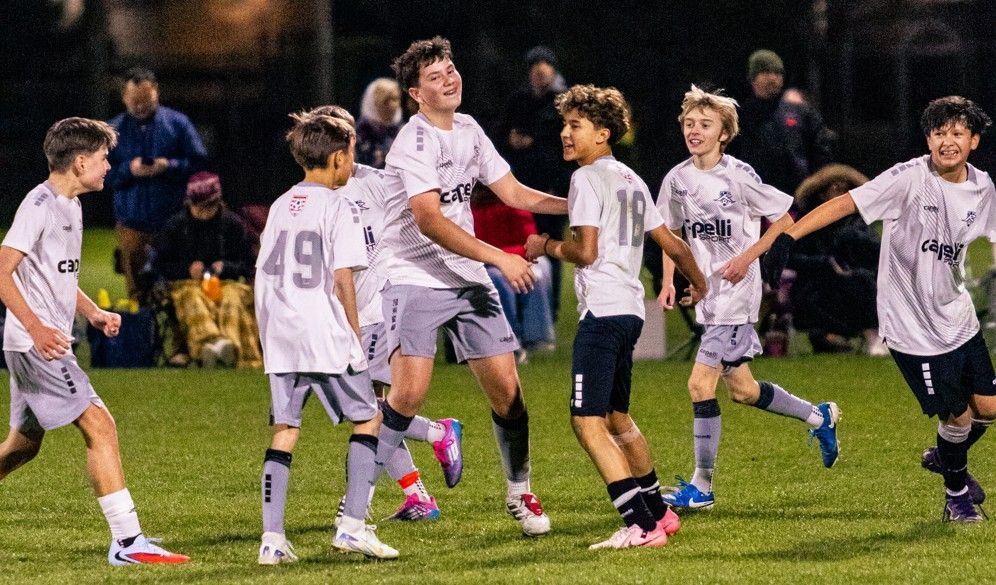 Rampage soccer team celebrating on the field, wearing gray and white uniforms, at night.