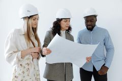 Three construction workers in hard hats reviewing a large blueprint together