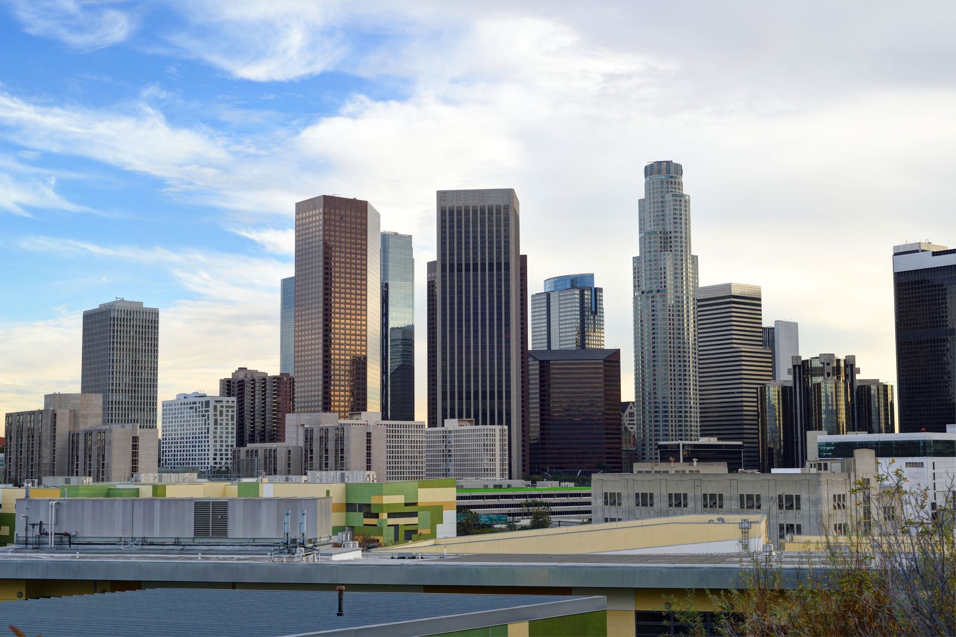 City skyline with modern high-rise buildings under a blue, partly cloudy sky.