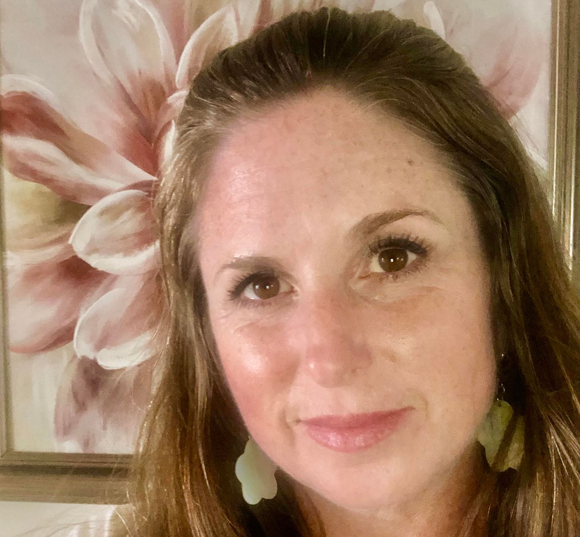 A woman is standing in front of a picture of a flower.