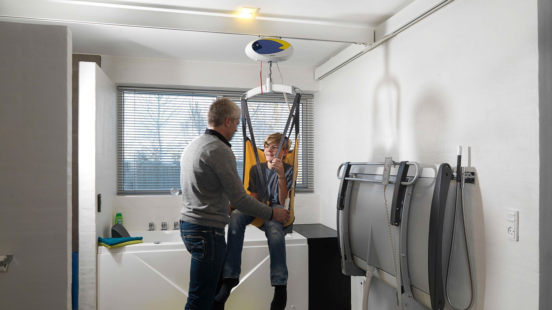Ein Mann hilft einem Kind in einer Trage im Badezimmer.