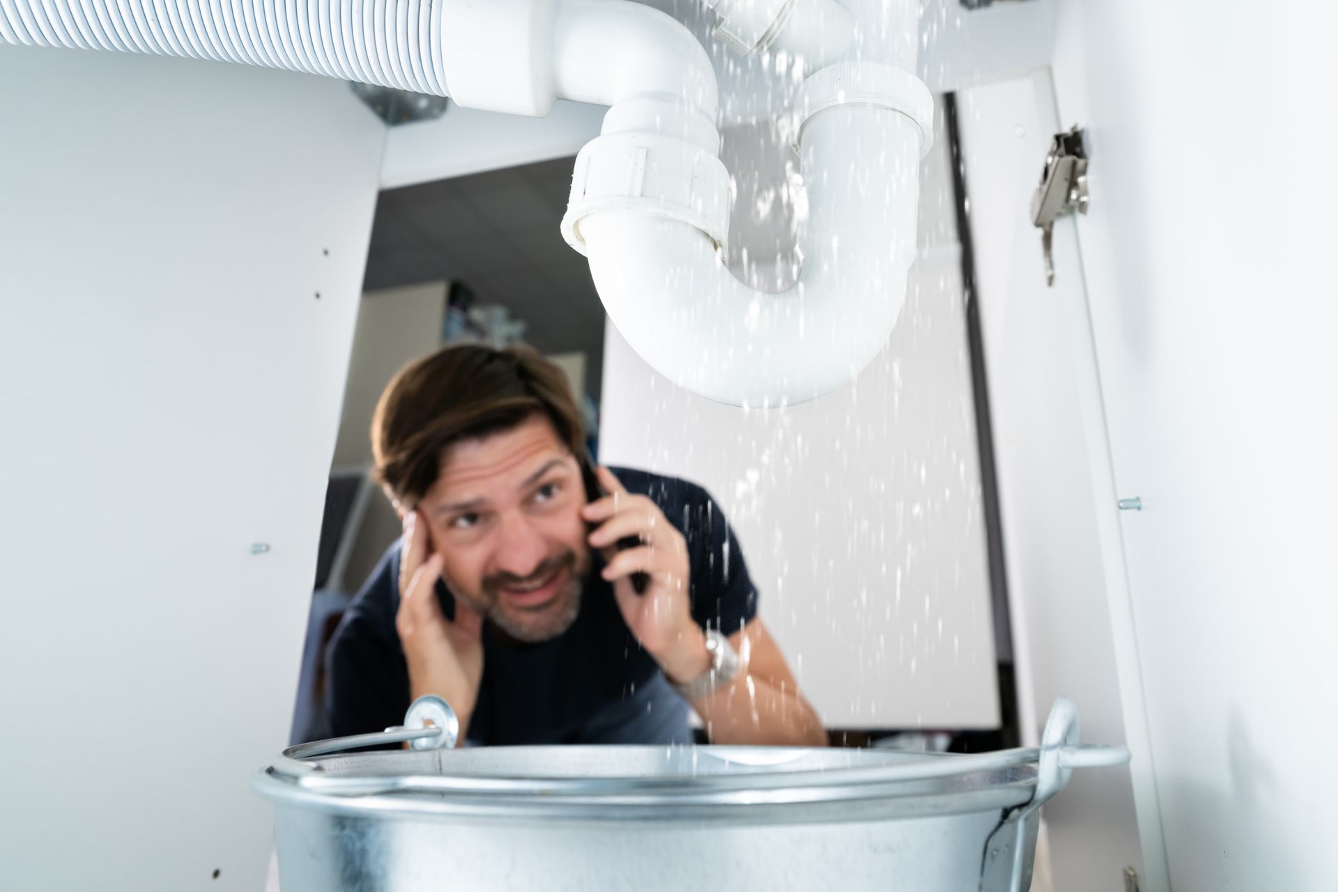 A man calls a plumber after spotting a water leak from the sink.